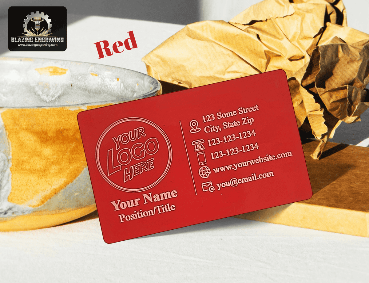 Custom laser-engraved metal business card in red finish with space for logo, name, and contact details, displayed on a white surface with gold and brown accents.