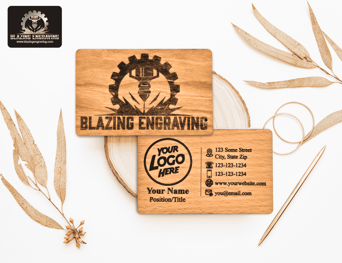 Wooden business cards for Blazing Engraving, featuring a gear and laser engraving logo on one side and customizable contact details on the other, displayed on a light surface with a gold pen and dried leaves.