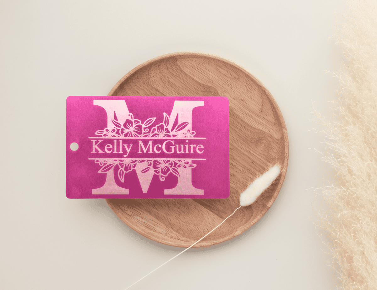 Pink personalized luggage tag with floral monogram and custom name engraving.