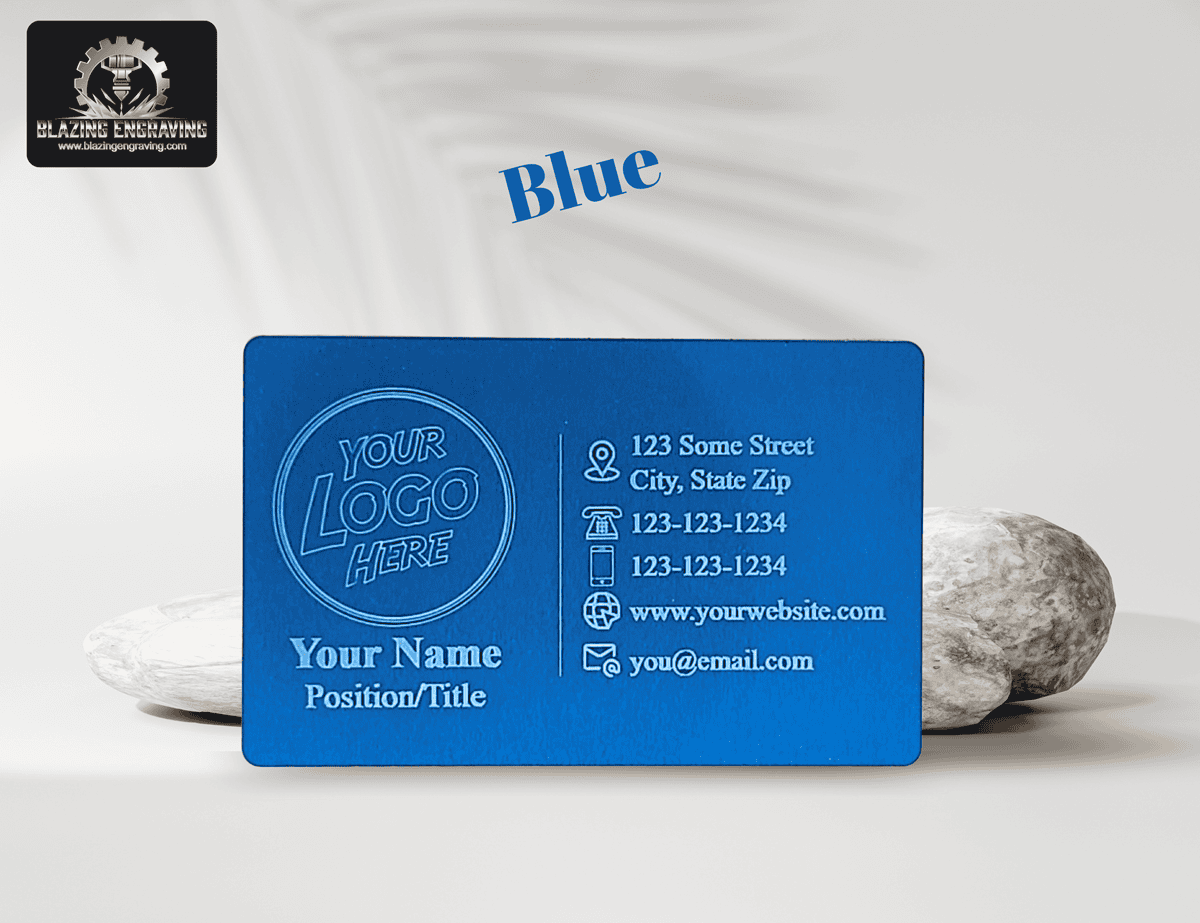 Custom laser-engraved metal business card in blue finish with space for logo, name, and contact details, displayed against a light background with natural stones.