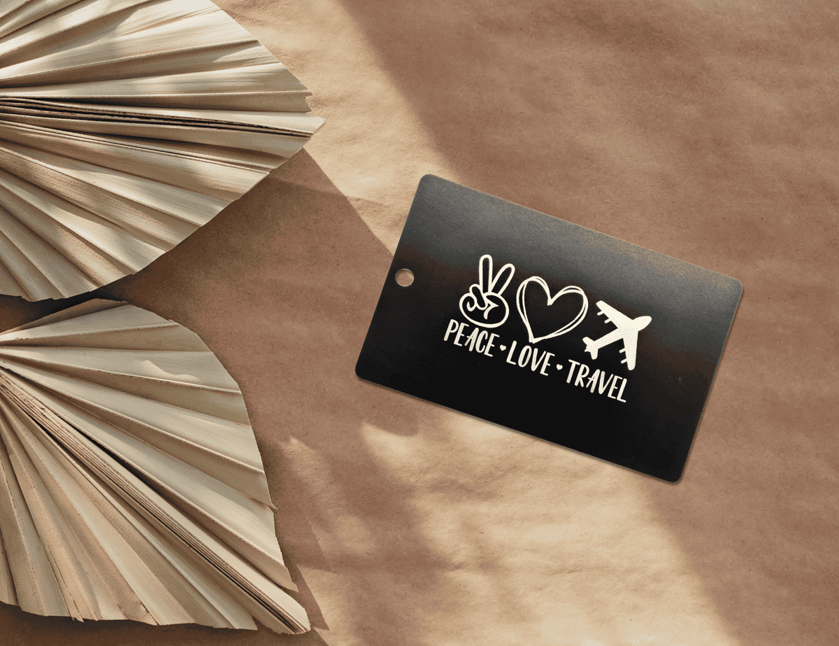 Black engraved luggage tag with “Peace Love Travel” icons and text.