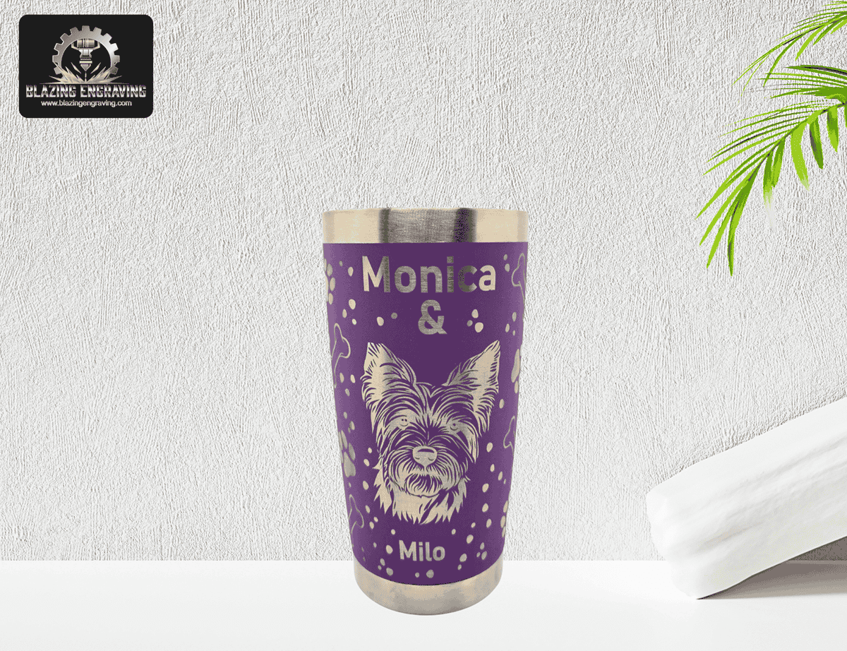 Purple stainless steel tumbler with silver laser-engraved design featuring the names ‘Monica & Milo’ and a detailed dog illustration. Blazing Engraving logo in the top left corner.