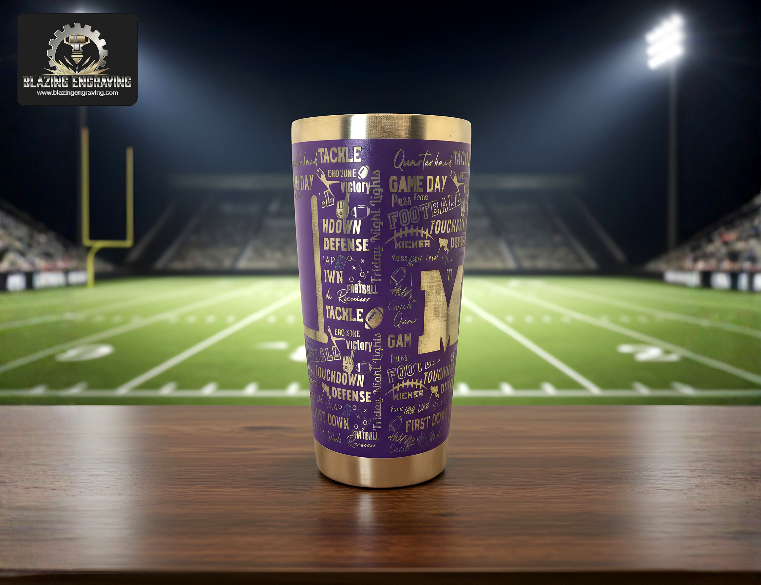 A stainless steel tumbler with a laser-engraved football mom design featuring football-themed words and a "MOM" graphic, displayed on a wooden surface with a football field and goal posts in the background. Blazing Engraving logo in the top left corner.